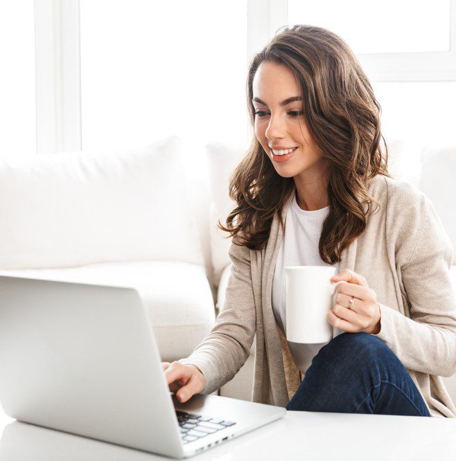 A woman in her mid 20s to 30s calculating a home loan on her laptop while having a coffee