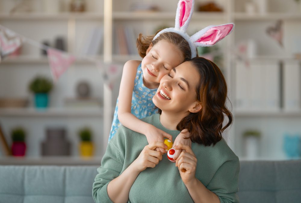 A little girl wearing bunny ears hugging her mum